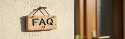 Ein rustikales Holzschild mit der Aufschrift FAQ hängt an einer Hauswand.