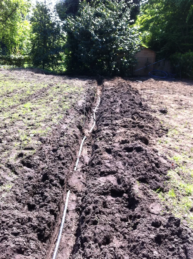 Langer Grabenzug mit durchgehendem Rohrstrang über die Gartenfläche