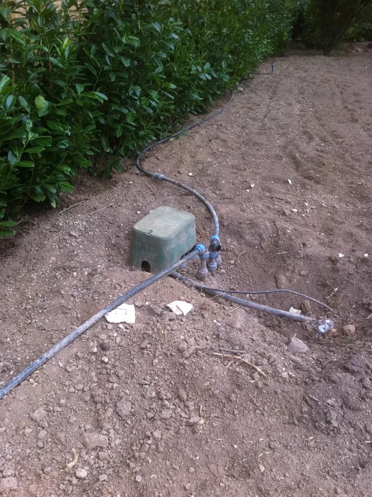 Ventilbox im Sandbett mit angeschlossener Leitung vor dem Verfüllen
