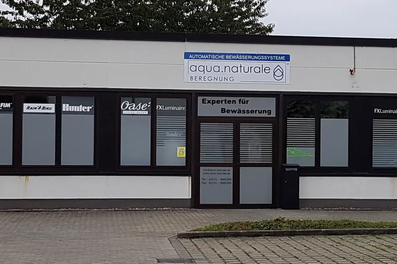Eingang des Abhollagers von aqua.naturale Beregnung, Hammer Landstraße 113 in Neuss, mit Firmenschild und Parkplätzen davor