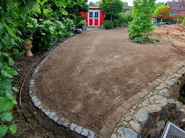 Fertig planierte Gartenfläche vor der Rasenansaat, eingefasst mit Pflastersteinen